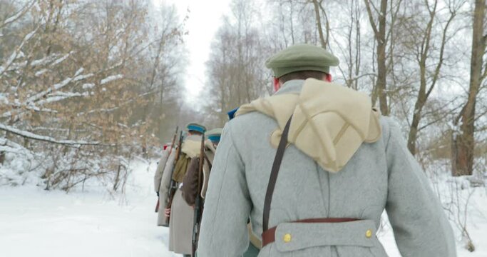Men Dressed As White Guard Soldiers Of Imperial Russian Army In Russian Civil War Times Marching Through Snowy Winter Forest. Historical Reenactment.