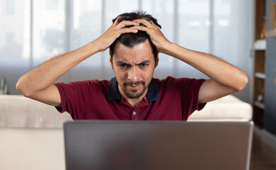 Hombre con señales de estrés observa preocupado su computadora portátil