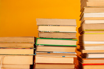 Fototapeta premium Tres pilas de libros en escalera sobre fondo naranja