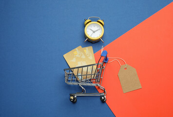 Shopping cart with credit cards on color background, flat lay. Sale concept