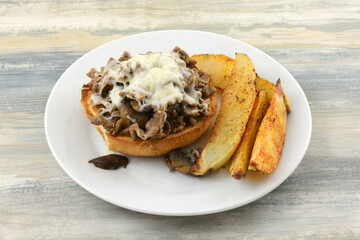 Open faced BBQ sliced beef sandwich with mushrooms and shredded cheese with potato wedges
