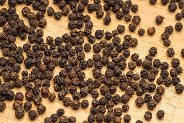 Black pepper on wooden background