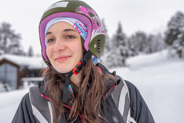 Women with brown hair smiling and looking, wearing ski wear and helmet, standing after arrival from the top of the mountain, ski centre stryn, norway, close-up, horizontal