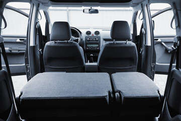 Open back door of family class minibus. The second row of seats are folded. Huge trunk of a large...