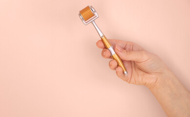 Mezoroller, dermaroller, mesotherapy skin tool for home use for meso therapy. pink background. female hand holds Roller set with microscopic needles. Stimulate collagen. beauty pain concept. 