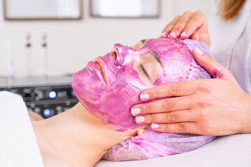 Beautician applies a woman a therapeutic cream on her face.  Cosmetologist making  massage the skin...