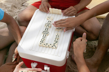 Man playing dominoes on top of a cooler at the beach,  Margarita Island, Venezuela