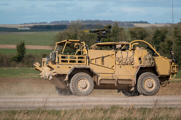 Obraz premium British army Supacat Jackal 4x4 rapid assault, fire support and reconnaissance vehicle in action across open countryside on a military battle training exercise