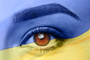 Double exposure of national flag and young woman, closeup of eye. Stop war in Ukraine