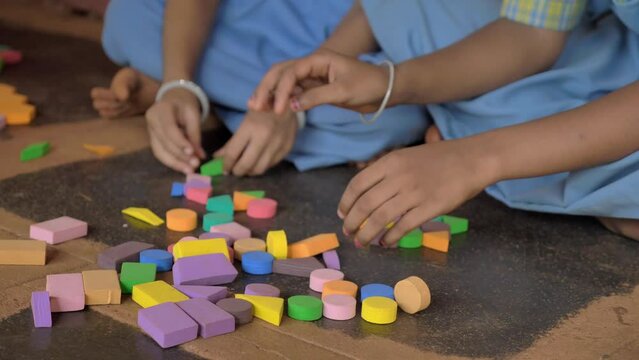 Close up shot of Indian Village school girls wearing uniform sitting together indoors in the premises busy playing group learning activity or constructive game.. concept of women's education.