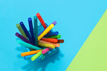 Yellow stationery felt-tip pens in a stand on a background of multi-colored cardboard paper.