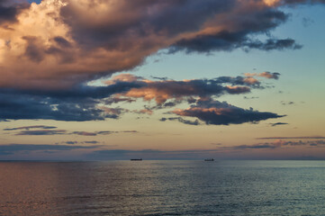 Naklejka na ściany i meble Sunset over the Tasman Sea, New Plymouth, New Zealand. Dark and orange clouds, calm sea and two ships on the horizon 