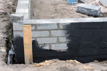 Damp proofing the outside foundation wall with a black black tar-based mixture