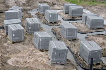Solid concrete blocks on wooden pallets on a construction site, concrete foundation footings...