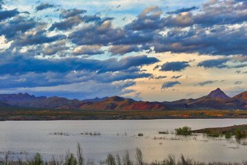 Sunset and cloudscape over Alamo Lake, Arizona, USA. The Rawhide Mountains light up in the evening sun. 
