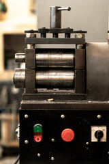 Close-up of gears of roll press. Rolling silver. Jewelry repair shop. Woman is out of focus in...