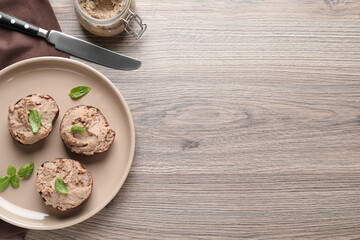 Slices of bread with delicious pate and basil on wooden table, flat lay. Space for text