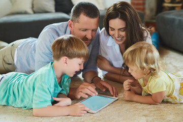 Using apps together as a family. Cropped shot of a young family using a tablet together on the floor in the living room at home.