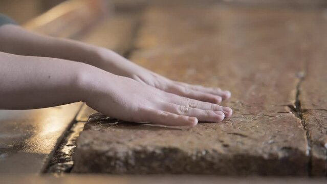 Close up of woman's hands on the Stone of Anointing in the Church of the Holy Sepulcher in Jerusalem.