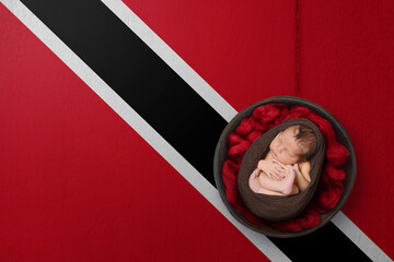 Newborn portrait on background in color of national flag. Patriotic photography concept. Trinidad and Tobago