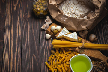 Italian food background with spaghetti, spiral pasta, mozzarella and camembert cheese, olives and olive oil, flour. Pasta set