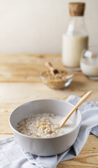 Healthy milky porridge from whole hulled grain oats in bowl with oat milk