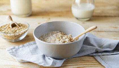 Healthy milky porridge from whole hulled grain oats in bowl with oat milk