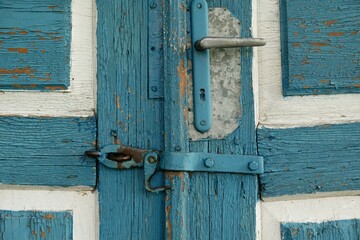 Close-up of the door handle on an old wooden door painted blue and white.