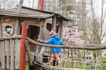 young girl playing in tree house in winter, sheltered by cold