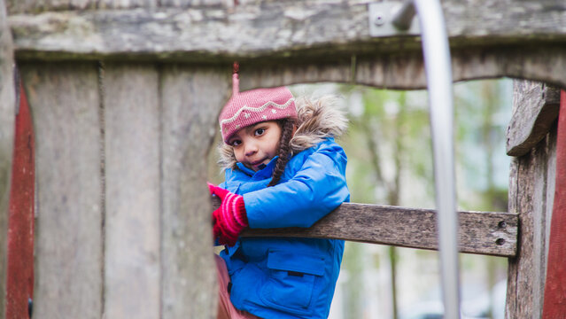 young girl playing in tree house in winter, sheltered by cold