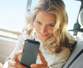Snapping a quick photo. Shot of a smiling girl taking a self portrait on her phone while she sits in her car.