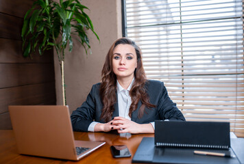 Business woman works in the office. A European girl is sitting at a table with a laptop and a diary.