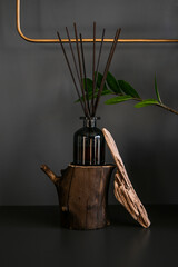 the diffuser with aroma sticks stands on a wooden stand on a dark background