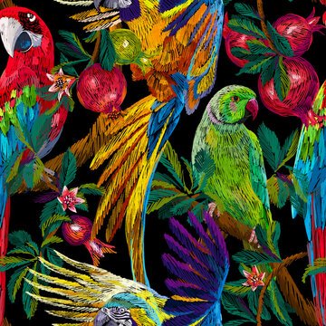 Tropical background. Exotic birds and fruits on the branches. Pomegranate tree and parrots. Colorful animals seamless pattern. Embroidery texture. Fashion design for textile, fabric and wallpaper.