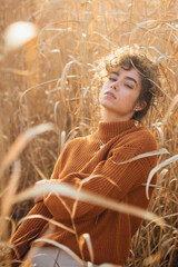Portrait of beautiful young woman with curly hair outdoor posing with sun light flare and sunset backlight