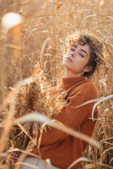 Portrait of beautiful young woman posing with sun light flare in the reed