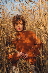 Portrait of beautiful young woman outdoor posing in the reeds and holding bouquet