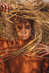 Portrait of a beautiful young woman posing outdoor and holds bouquet of reeds