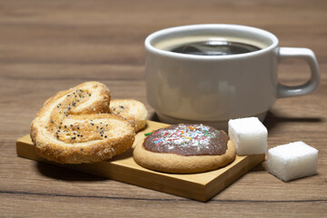 Cookies with chocolate icing, refined sugar and black coffee on the table