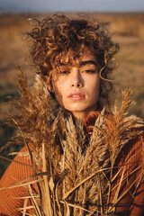 Portrait of a beautiful young woman with curly hair enjoying the sun