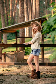 Smiling tween girl standing near animal stall in country estate in forest