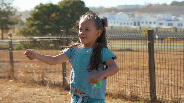 Ni&ntilde;a feliz jugando volando el papalote el cometa con el aire disfrutando en el parque al aire libre en el exterior aprendiendo conociendo el mundo