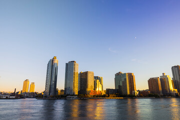 Fototapeta na wymiar Sunset light illuminates row of the luxury high-rise residential buildings in Long Island City beyond the East River from Franklin D. Roosevelt Four Freedoms Park in Roosevelt Island on November 2021 
