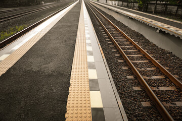 railroad tracks in a train station with building sides for passengers to easily get on the train