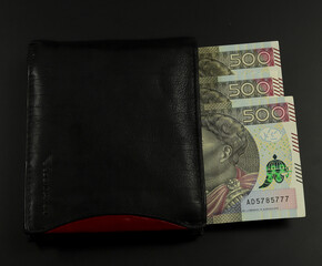 Pieniądze w portfelu. Duża kwota - banknoty po 500 złotych. Czarny portfel, kolorowa waluta polska.