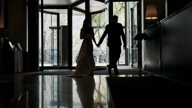 a girl with a man leaves the hotel lobby in the backlight