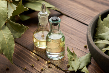 Bottles natural bay laurel essential oil. Wooden bowl of dried laurel leaves. Branch and twigs of green bay leaves.