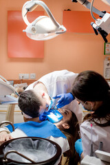A dentist treats a woman's teeth using a cofferdam. Dental equipment