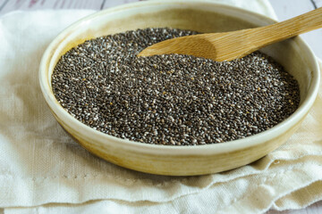 Bowl with chia seeds and wooden spoon. Rustic wooden table