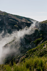 Wild green climbs under low clouds against clear blue sky. Incredible nature. Wonderful nature on the island in the mountains